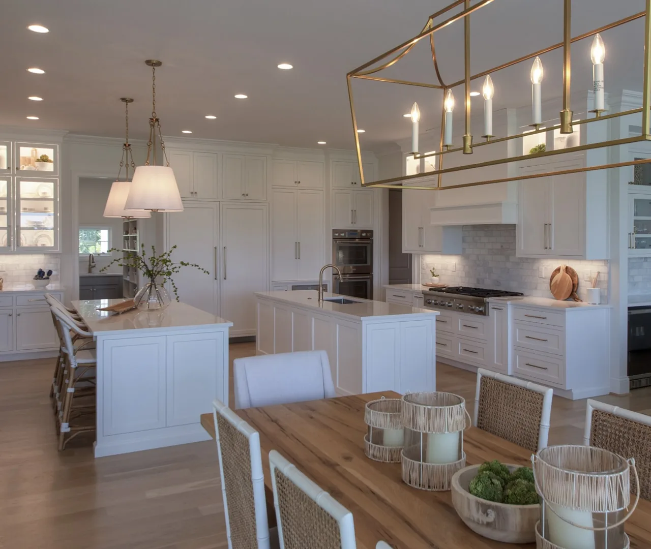 Open kitchen with two islands, cane counter stools and a brass lantern over the dining table
