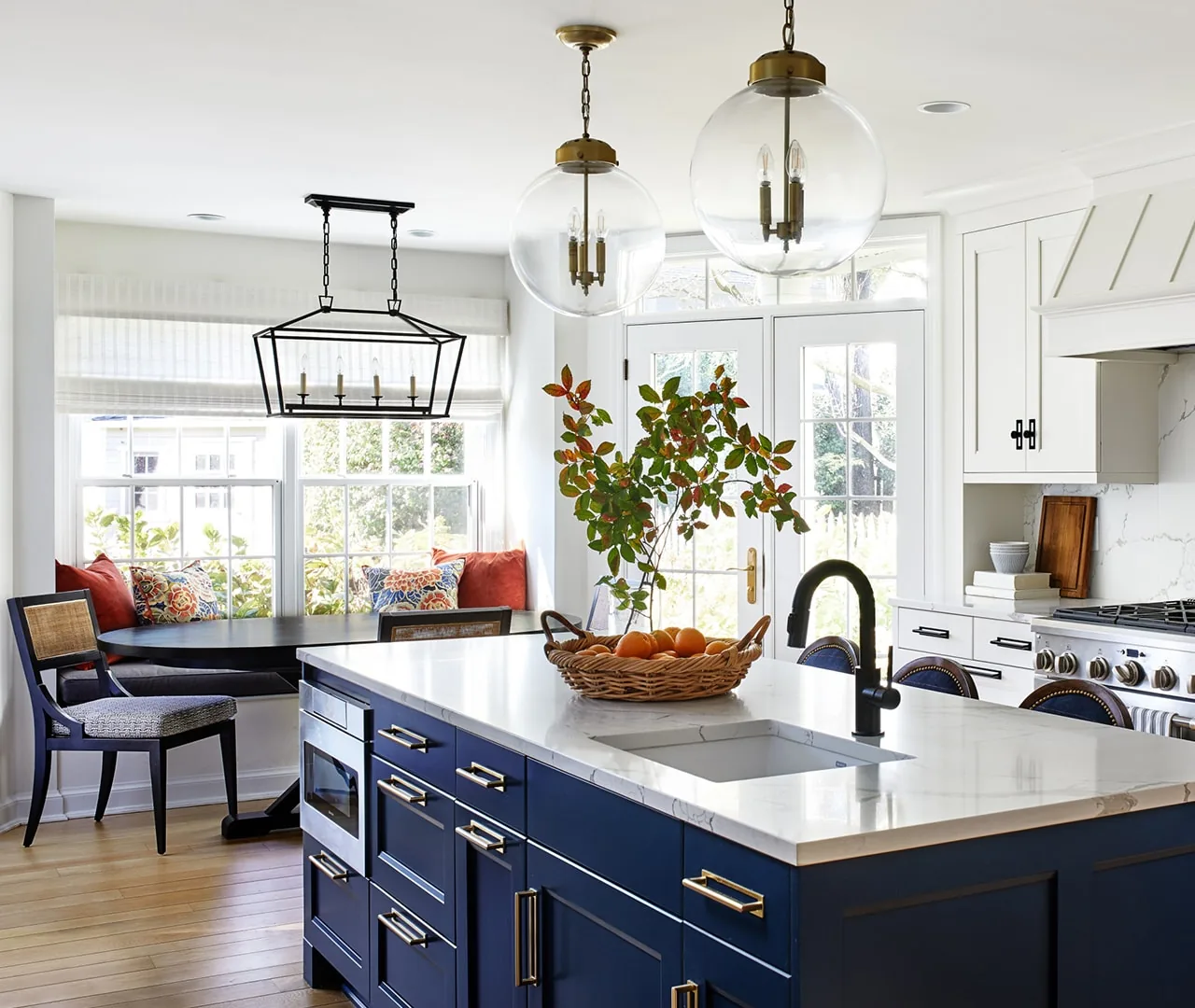 Kitchen with a navy island, brass hardware and a window seat in the breakfast area